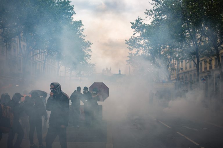 Manifestation contre la réforme des retraites, 1er mai 2023. Le ton monte encore d&rsquo;un cran jusqu&rsquo;au devenu traditionnel mur de grilles et les  canons à eau à l&rsquo;entrée de Bellecour où se joue une bataille toujours aussi étrange, jet de pierres contre canon a eau et jet d&rsquo;eau jusqu&rsquo;à épuisemment.
